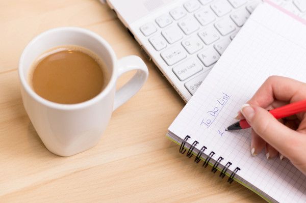 Handwriting a to-do list beside coffee, capturing the essence of energized task management.