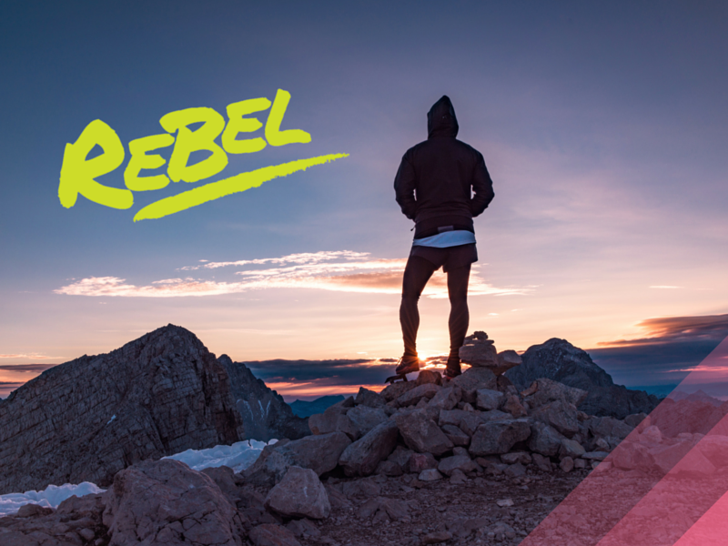 Silhouetted figure stands atop mountain at sunrise, 'REBEL' boldly inscribed, symbolizing empowerment and activity.