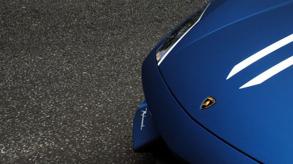 Close-up of a blue sports car's hood, showcasing sleek design and performance symbolism.