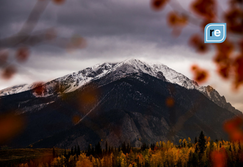 Snow-capped mountain behind autumn-colored forest, symbolizing the peak of deals on Black Friday 2016.