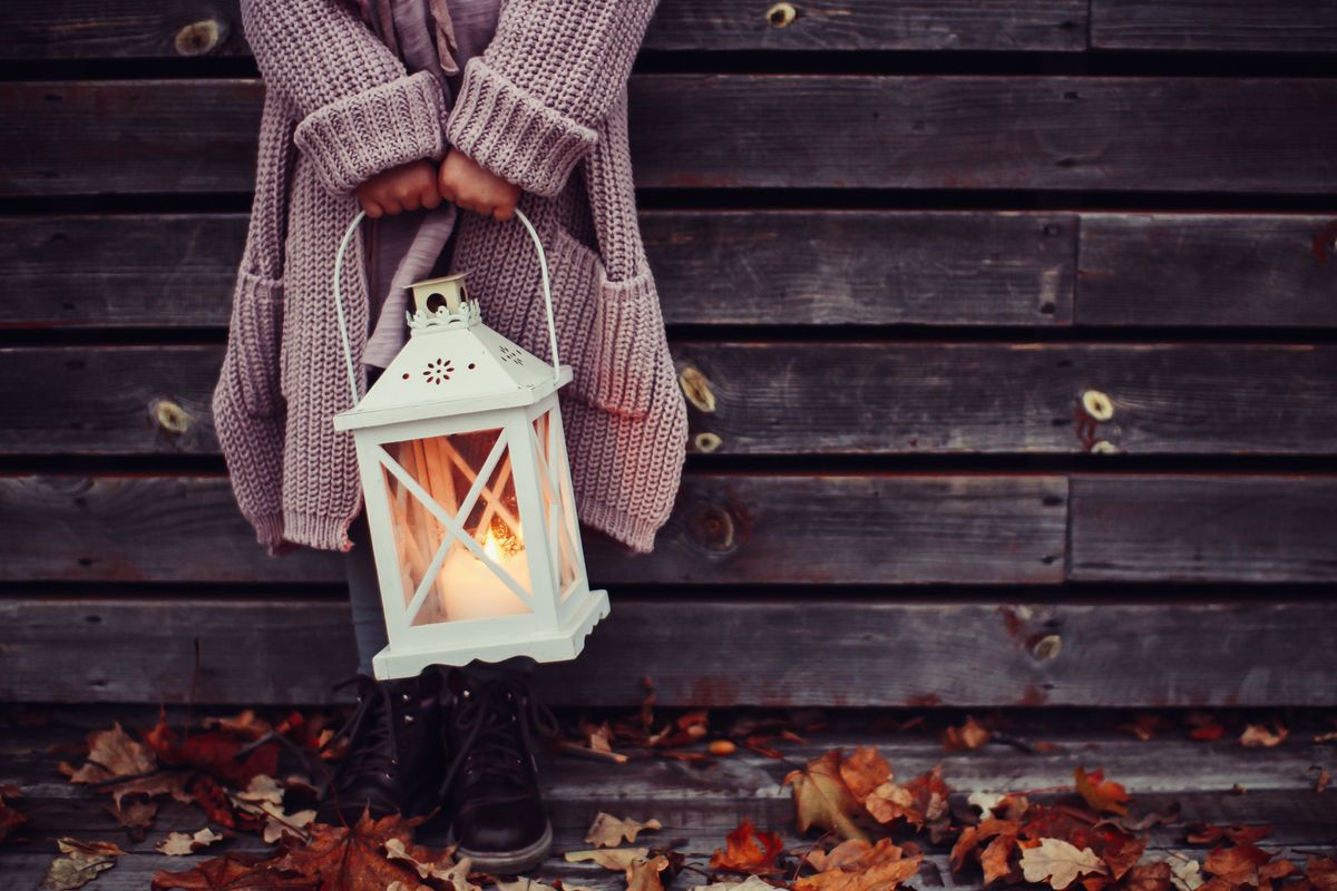 Person holding lantern against autumn leaves, a metaphor for finding guidance and warmth in balance and recovery.