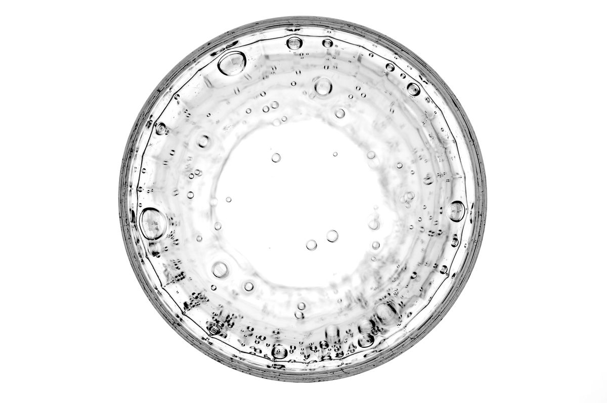Top-down view of clear water with bubbles in a petri dish, symbolizing hydration's importance for cognitive function.