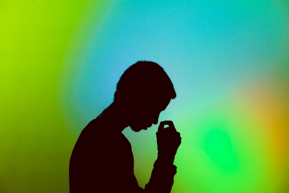 Person in contemplation against a soft gradient background, evoking a sense of introspection and calm for stress management.